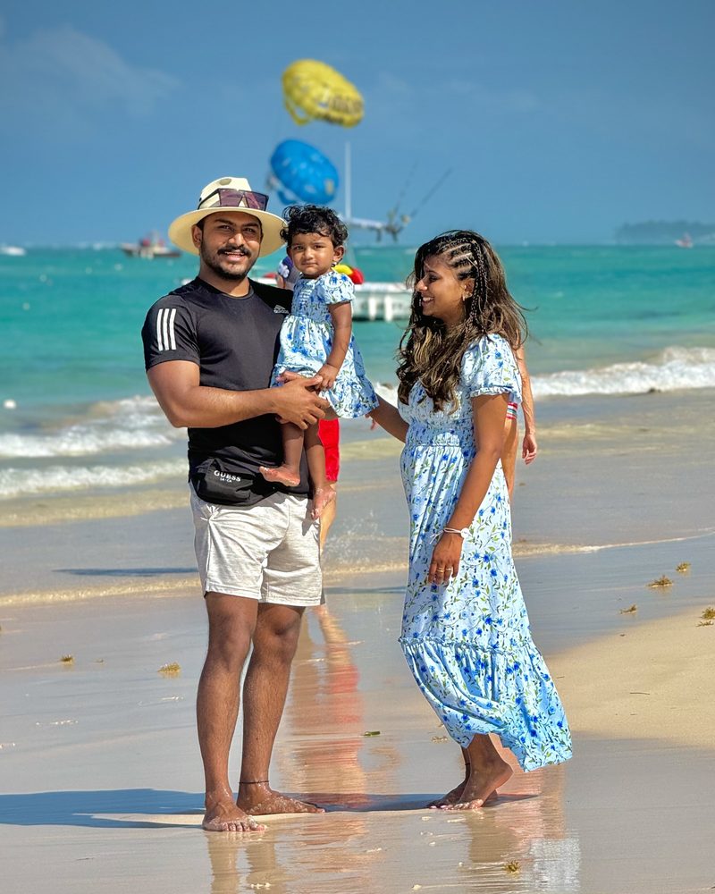 Jo with his family on a sunny beach, turquoise water and a parasail behind them